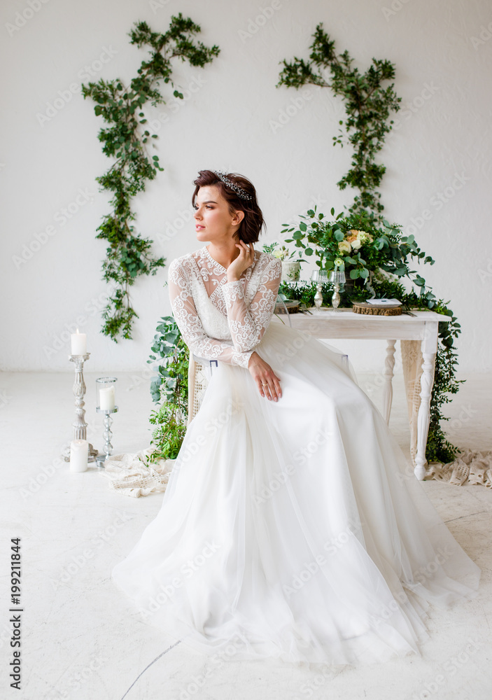 Beautiful wife sitting in a white room decorated with green decor in a botanical style Beautiful wife sitting in a white room decorated with green decor in a botanical style