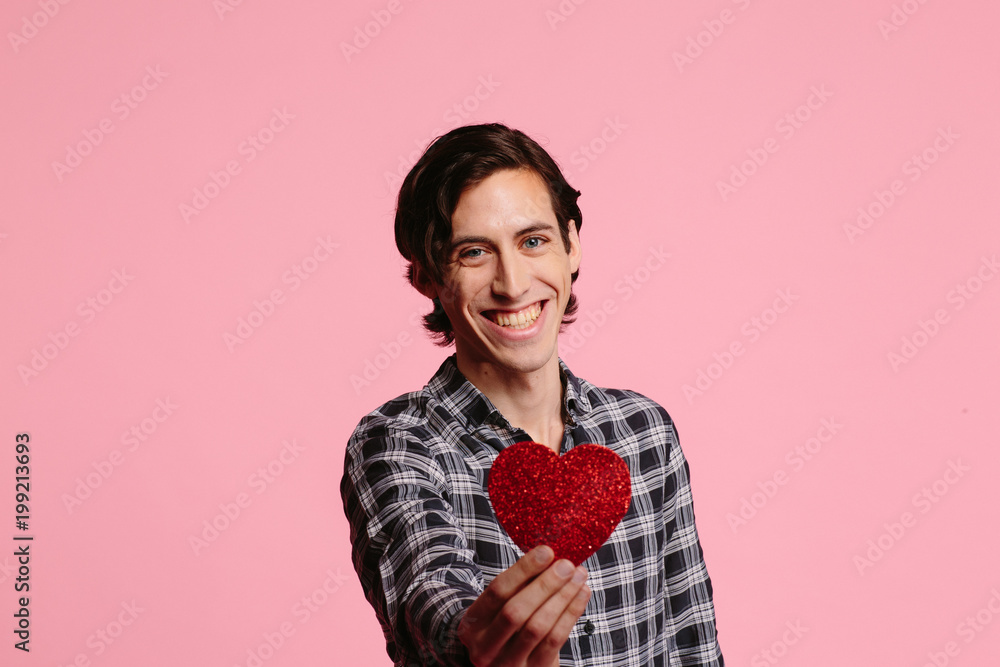 Portrait of a young smiling man holding out a heart, be my valentine Portrait of a young smiling man holding out a heart, be my valentine