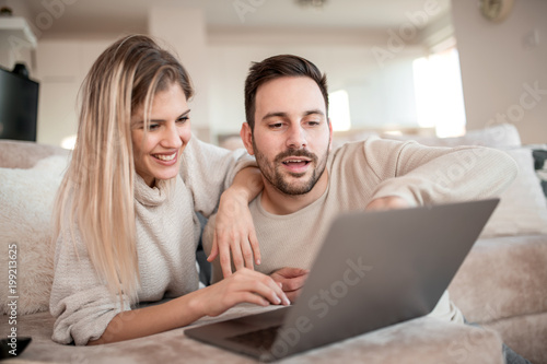 Beautiful young couple is using a laptop at home