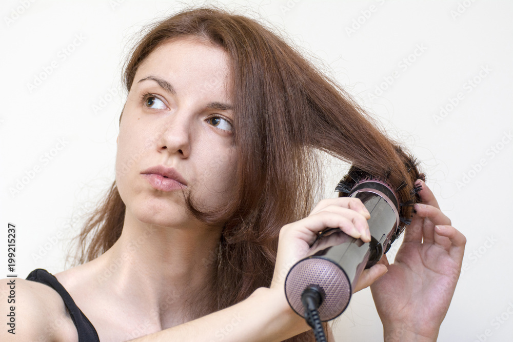 Fototapeta premium Redhead model using an air styler brush to dry and style her hair