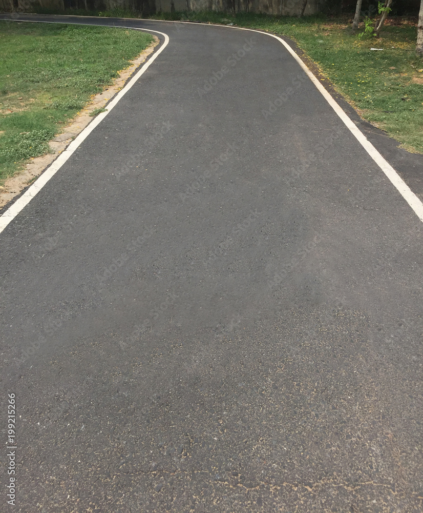 Black asphalt winding Road transport going to the distance with white line at public park
