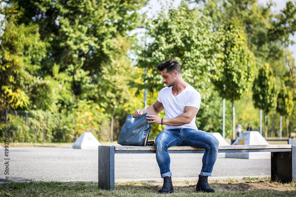 Attractive muscular man in city park in a nice summer day Attractive muscular man in city park in a nice summer day