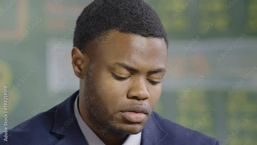 Black man looking down and away from camera with serious expression Black man looking down and away from camera with serious expression