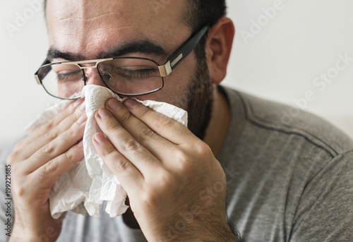 Fototapeta Naklejka Na Ścianę i Meble -  Man sneezing into tissue paper