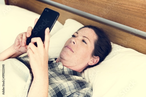 A woman using a mobile phone in bed