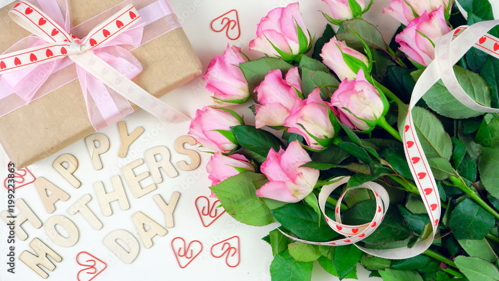 Mother's Day overhead with gift and pink roses on white wood table background with wooden letters spellling Happy Mother's Day. Mother's Day overhead with gift and pink roses on white wood table background with wooden letters spellling Happy Mother's Day.