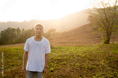 Young handsome asian man in white T-Shirt stands in a field © bignai