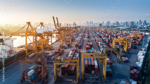 Logistics and transportation of Container Cargo ship and Cargo plane with working crane bridge in shipyard at sunrise, logistic import export and transport industry background