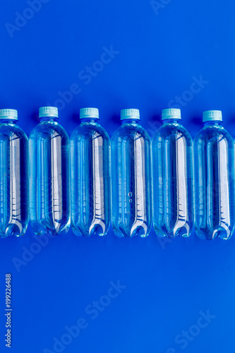 Drinking water in bottles on blue background top view copy space