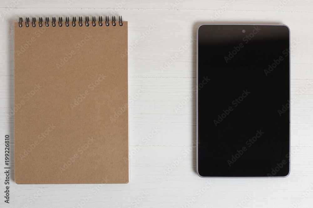 Fototapeta premium Pen of a natural wood smartphone and notebook on a white table.