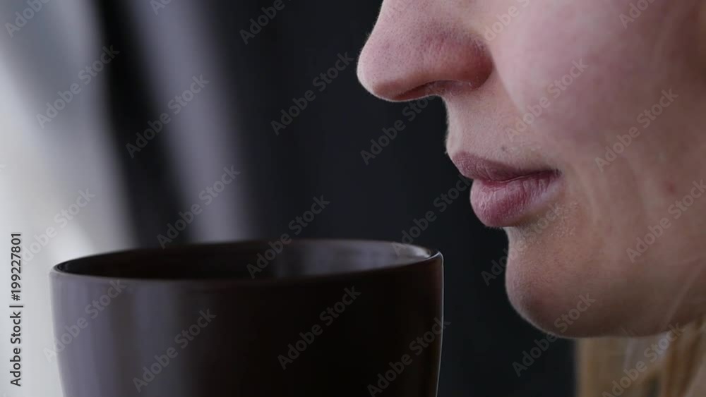Young woman drinks coffee or tea near the window. slow motion Young woman drinks coffee or tea near the window. slow motion