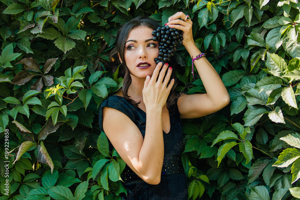 Portrait of young sexy brunette with black grapes. Copy Space. Portrait of young sexy brunette with black grapes. Copy Space.