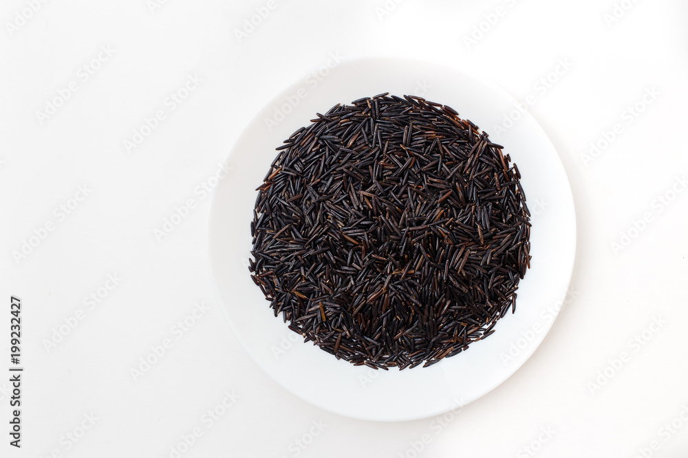 black wild long raw rice on white plate on white background black wild long raw rice on white plate on white background