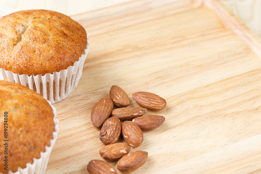Banana cup cake and roasted almonds are placed on wooden floors with copy space Banana cup cake and roasted almonds are placed on wooden floors with copy space
