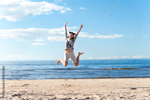 Young cheerful jumping teenage girl excitement at seaside
