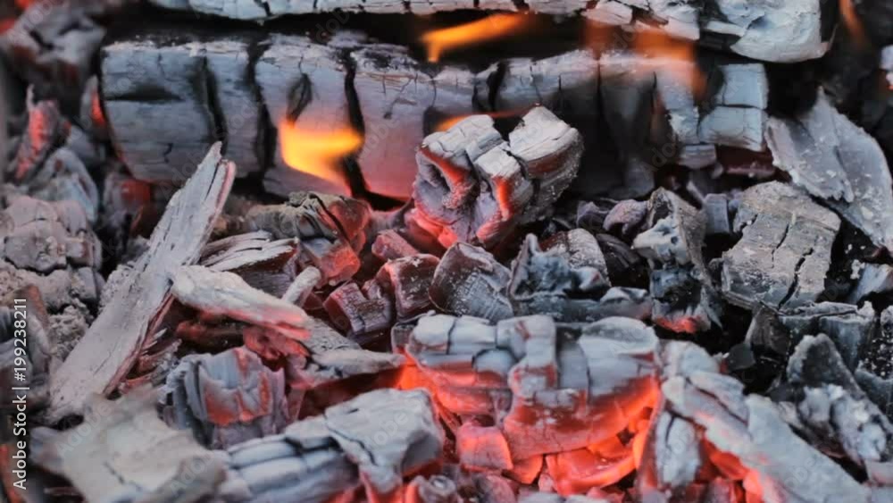 Close view at a glowing charcoal and flame in the barbecue grill Close view at a glowing charcoal and flame in the barbecue grill