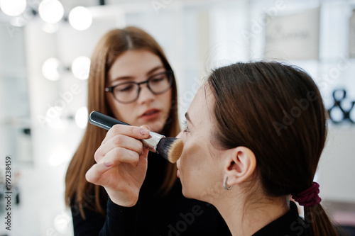 Make up artist work in her beauty visage studio salon. Woman applying by professional make up master. Beauty club concept.