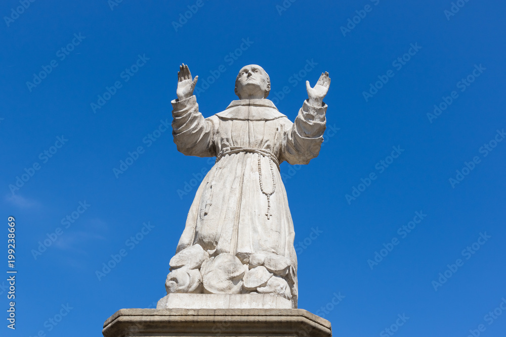 A statue of Saint Wojciech against a cloudless blue sky