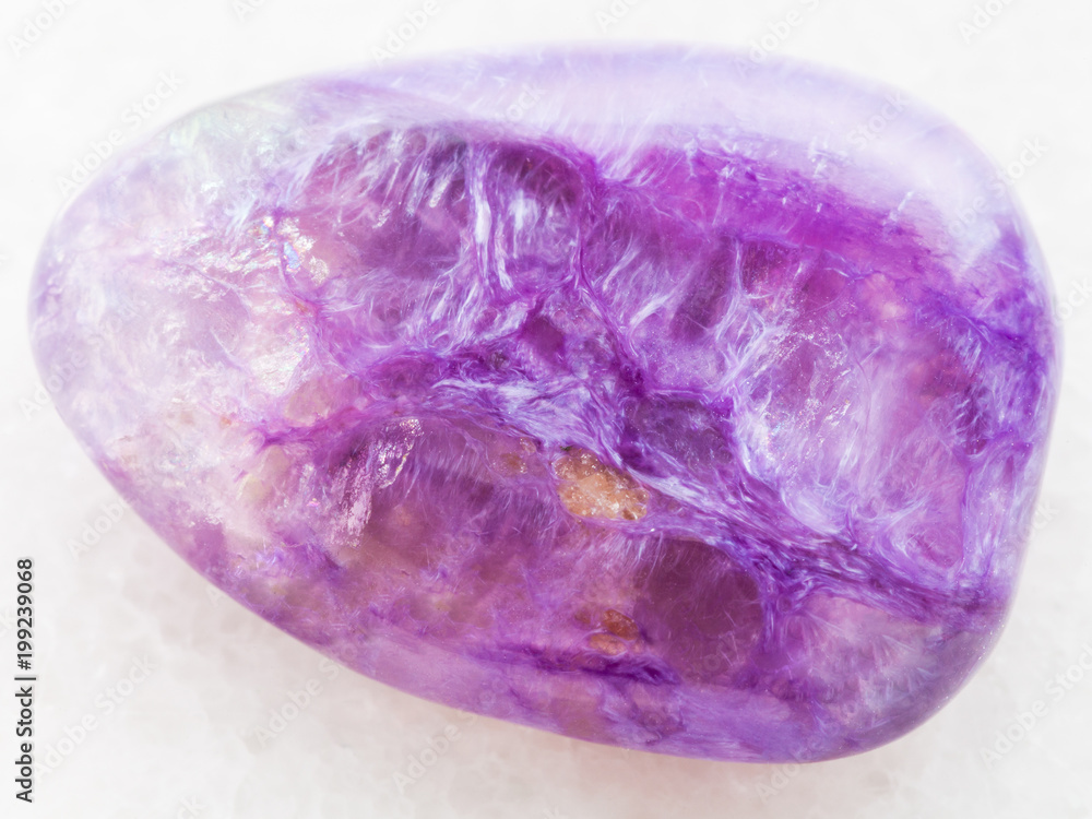 tumbled Charoite gemstone on white marble tumbled Charoite gemstone on white marble