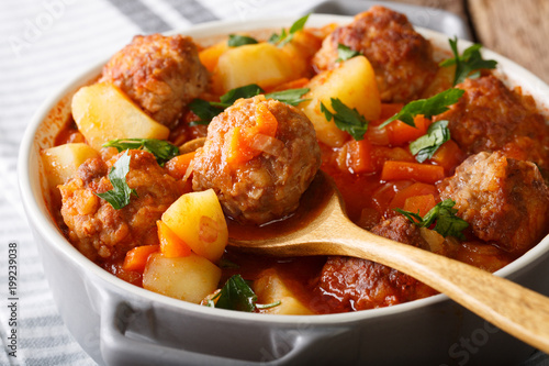 Meatballs stewed with vegetables in a tomato sauce close-up in a pot. horizontal