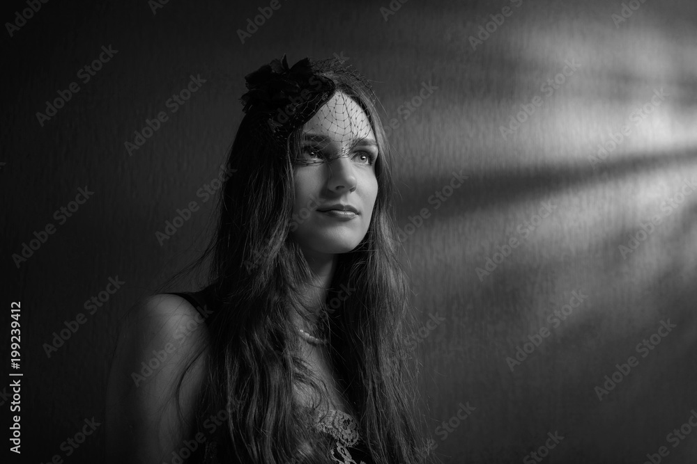 Dramatic portrait of a beautiful woman in hat with veil .
