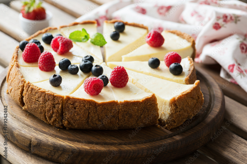 Classical Cheesecake with fresh berries on wooden board, selective focus, horizontal composition Classical Cheesecake with fresh berries on wooden board, selective focus, horizontal composition
