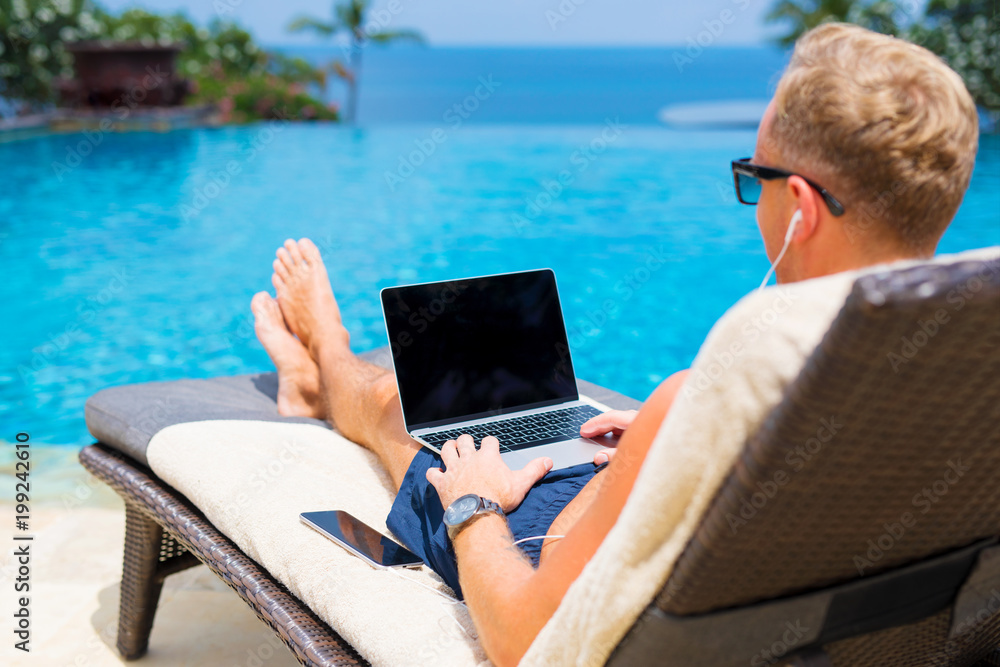 Man working with laptop by the pool