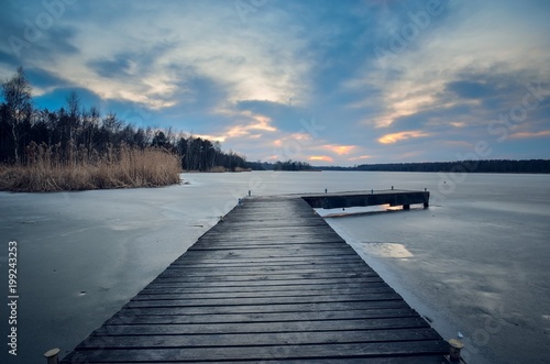 Fototapeta Naklejka Na Ścianę i Meble -  Evening winter landscape. Wooden pier over a beautiful frozen lake.