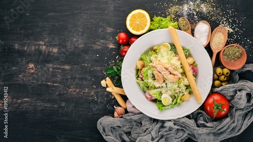 Chicken Salad and Fresh Vegetables. Caesar. Top view. On a black wooden background. Copy space.