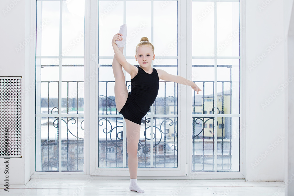 Little Child Girl gymnast doing stretching in a bright room on a happy and cute window background Little Child Girl gymnast doing stretching in a bright room on a happy and cute window background