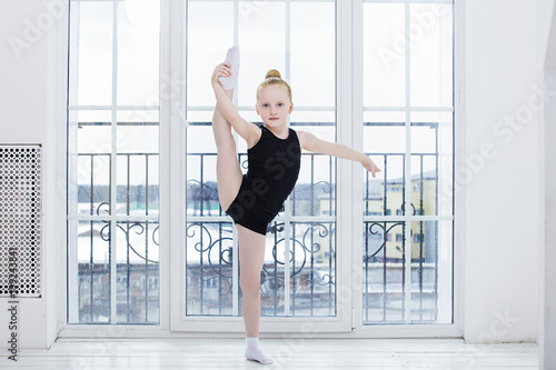 Free Download Little Child Girl gymnast doing stretching in a bright room on a happy and cute window background - GFXLoad