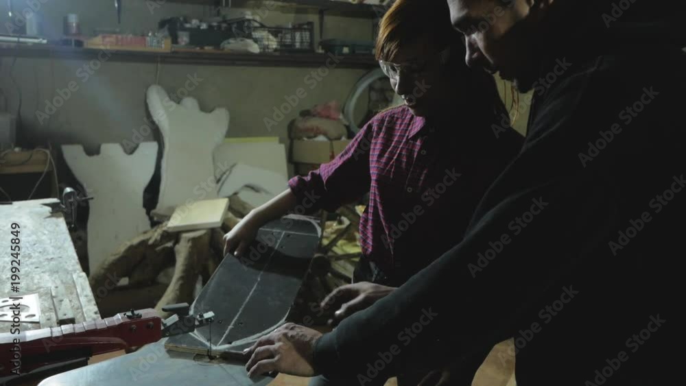 Young man and woman work in workshop with electric tools Young man and woman work in workshop with electric tools