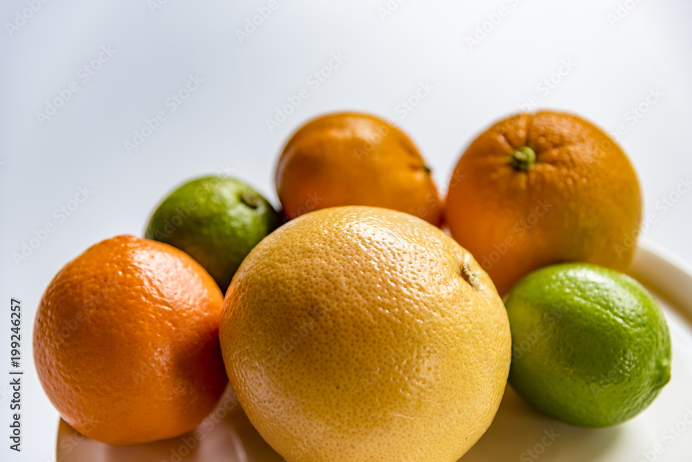 Fresh citrus fruits on a white background. Orange, grapefruit, lemon, lime and mandarin fruits on a white plate. Fresh citrus fruits on a white background. Orange, grapefruit, lemon, lime and mandarin fruits on a white plate.
