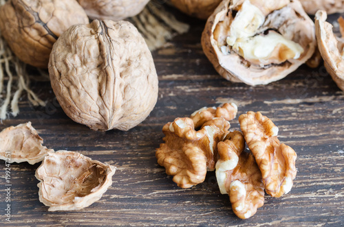 Walnut kernels and whole walnuts on wooden table. Healthy and nutritive snack. Copy space.