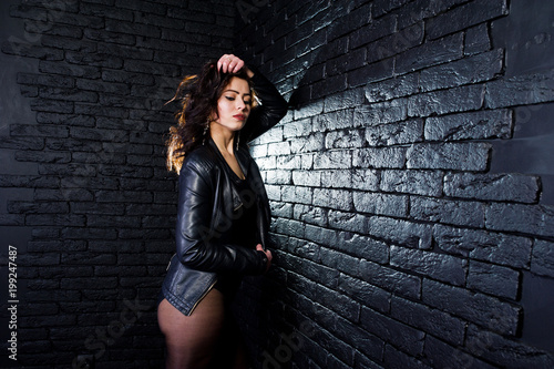 Studio portrait of sexy brunette girl in black leather jacket against brick wall. © AS Photo Family