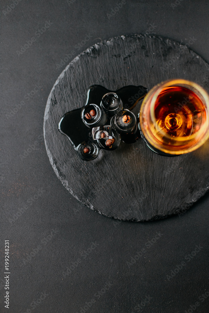 a glass of cognac on a black background, apperetiv with ice and coffee beans, view from above a glass of cognac on a black background, apperetiv with ice and coffee beans, view from above