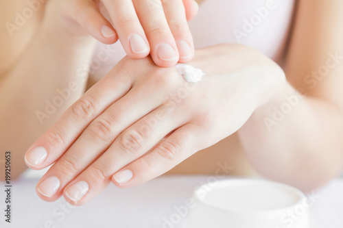 Groomed woman's hand applying moisturizing cream on her hand. Cares about clean and soft hands skin. Healthcare concept.