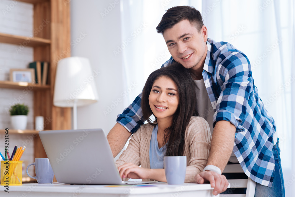 Online opportunities. Happy merry couple staring at camera and woman using laptop Online opportunities. Happy merry couple staring at camera and woman using laptop
