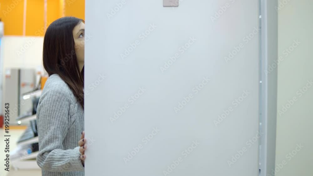 Brunette woman chooses a refrigerator in a home appliance store. Brunette woman chooses a refrigerator in a home appliance store.