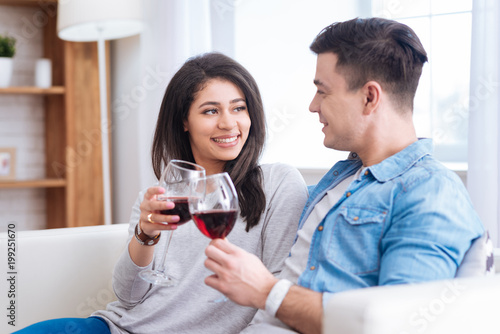 Red wine. Inspired optimistic couple clinking glasses with wine while smiling © zinkevych