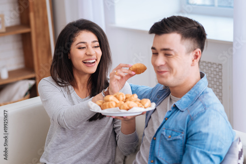 Eat one more. Attractive gay holding plate while woman feeding man