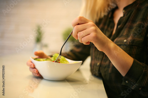 Close-up of woman’s hands eating fresh salad.