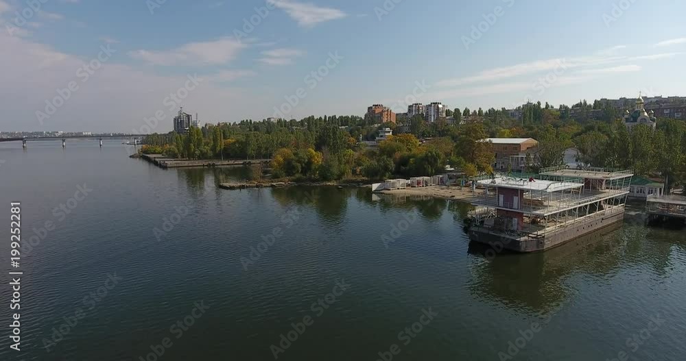 Aerial view river bank with a closed beach and buildings among green trees Aerial view river bank with a closed beach and buildings among green trees