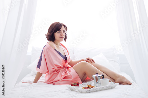 young brunette girl breachfast white bedroom photo