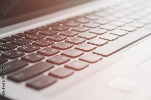 Laptop keyboard with focus on the keys, and warm toned background bokeh