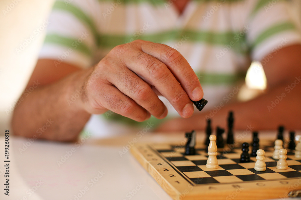 Fototapeta premium Senior man playing chess, close-up of hand.