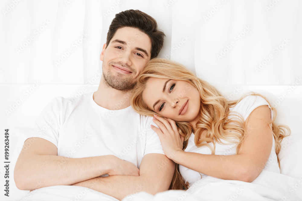 Loving couple lies in bed indoors at home Loving couple lies in bed indoors at home