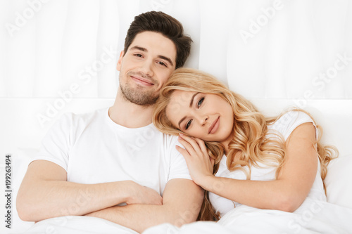 Loving couple lies in bed indoors at home