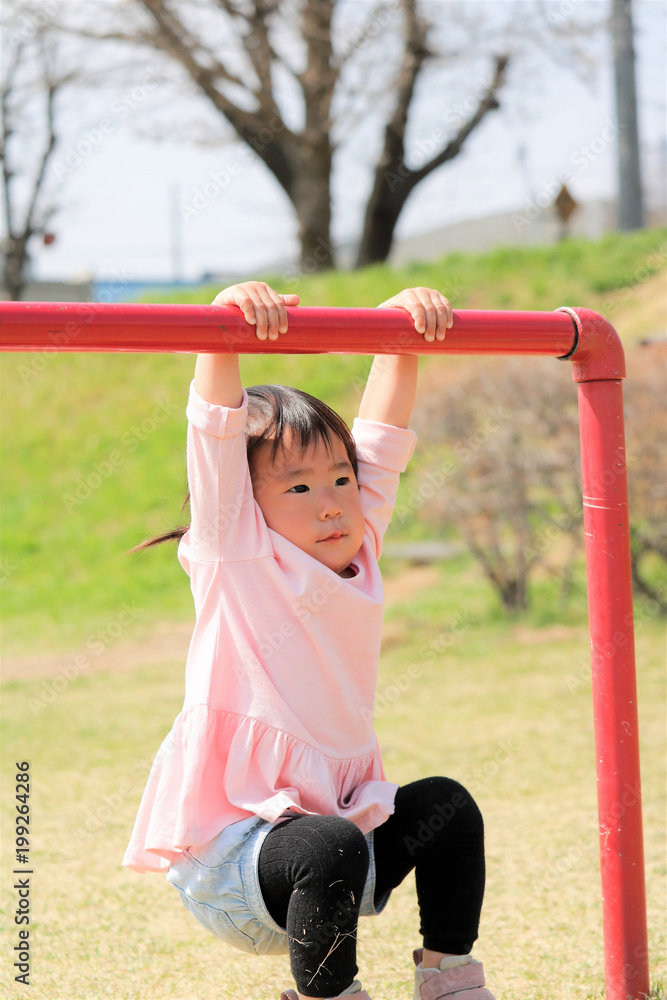 Fototapeta premium 遊具にぶら下がる女の子