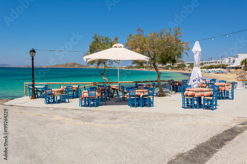 Tables with chairs in typical Greek tavern with view on sea bay near Agia Anna beach  Naxos Island. Greece.